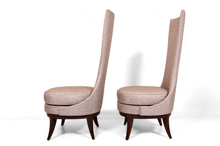 For your consideration a pair of high back chairs. 
No label from the maker present.  New upholstery with linen texture, satin finish, dominant color light brown.  Mounted in sculptural wood base with dark walnut finish.