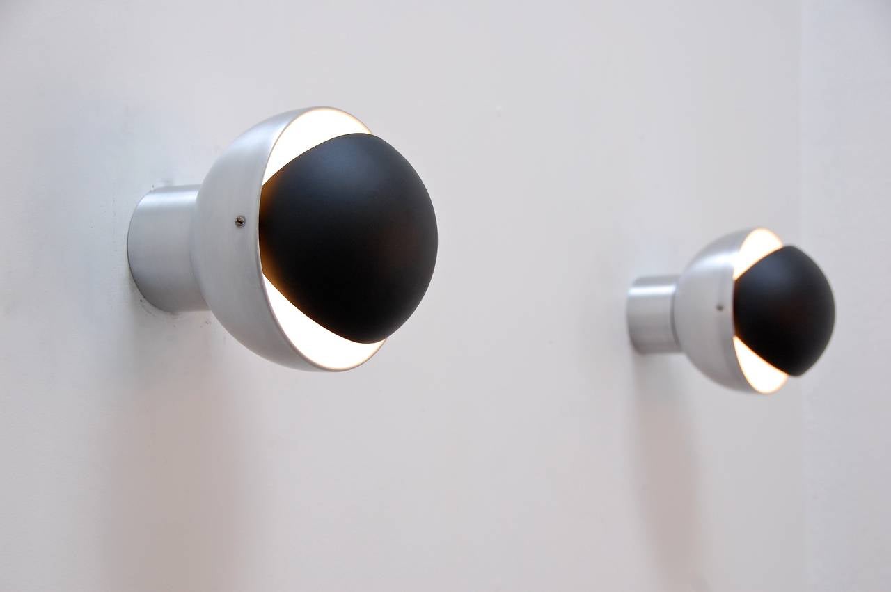 Four amazing sconces from Holland by RAAK. Two-tone finish of satin and painted balk aluminium. Shades articulate 180 degrees creating an eyelid effect. Wired for use in the US. Single medium based socket per sconce.