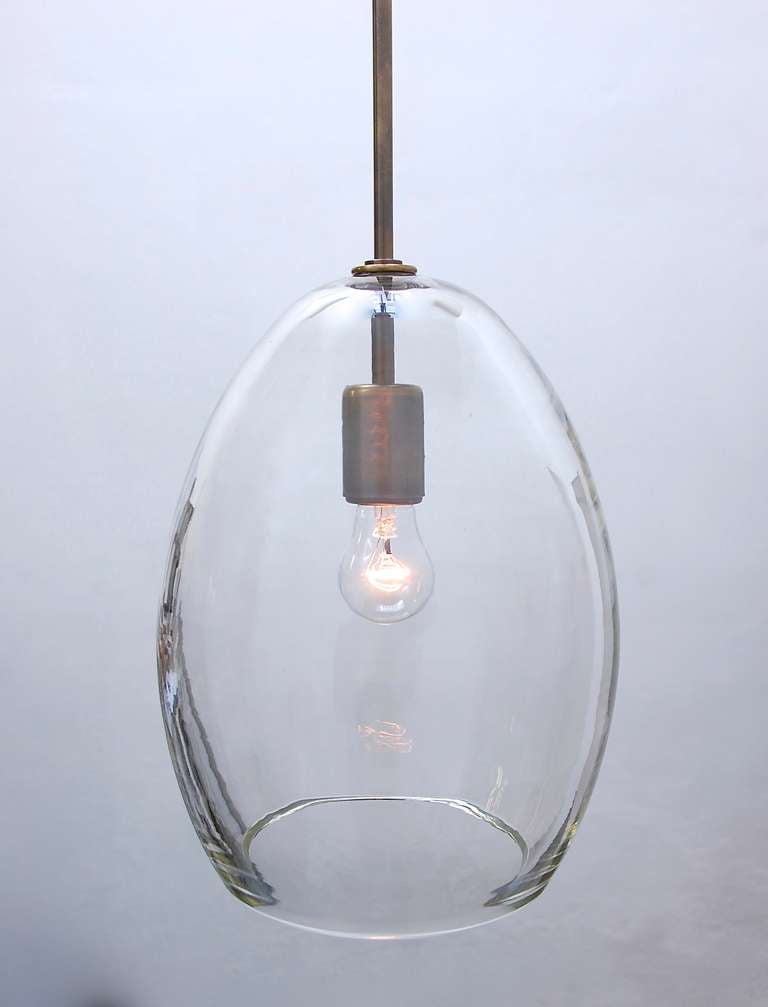 Handblown clear large glass drop pendant(s) with aged brass stem and canopy.

Measures: Shade height 12