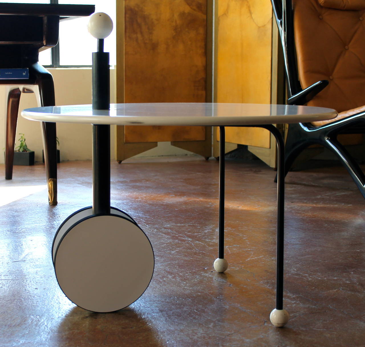 A wonderful and rare table by Michele De Lucchi. White lacquered laminated wood table top with a rolling base and balls on feet and on outcrop. The wheels turn and are lined with rubber.
Black painted steel frame.

Michele De Lucchi was born in
