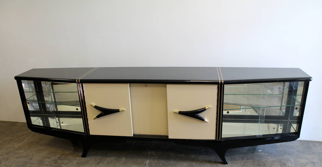 Unusual and beautiful credenza designed or custom build by Eugenio Escudero.
Brass accents/inlay, asymmetrical legs and door pulls, drawers, shelves and mirrored display section on each side.
Mexican mahogany, brass, lacquer, veneer, mirror and