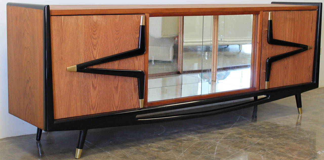 Beautiful custom credenza with mirrored section in the middle, sculptural handles and base.
By Eugenio Escudero.
Mexico City, circa 1950s.
Beautiful solid brass accents.
Mexican mahogany, brass, lacquer, veneer, mirror and glass.