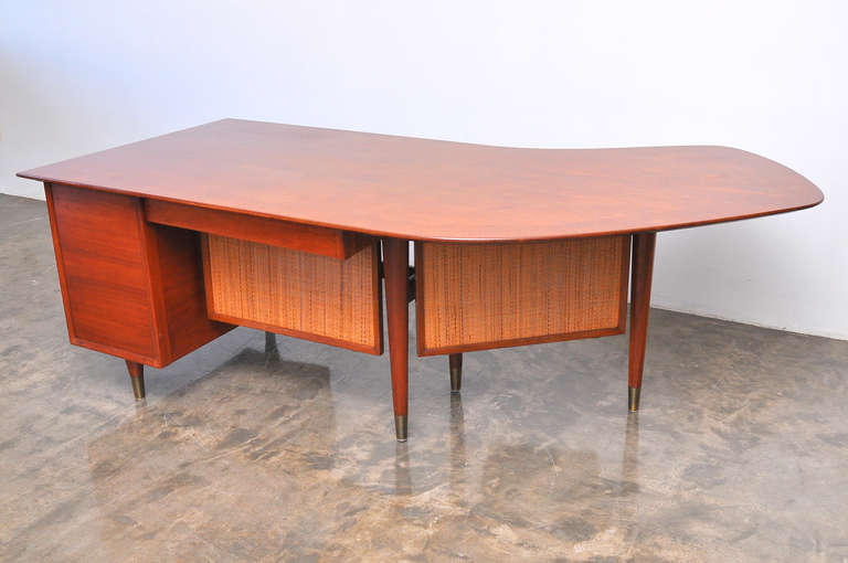 Beautiful Mid-Century Modern boomerang desk circa 1950s.  It is solid walnut, with a left return and cane screens. Has been kept in great condition and is rich in color. It also has secret locking mechanism for the drawers.
This large spacious