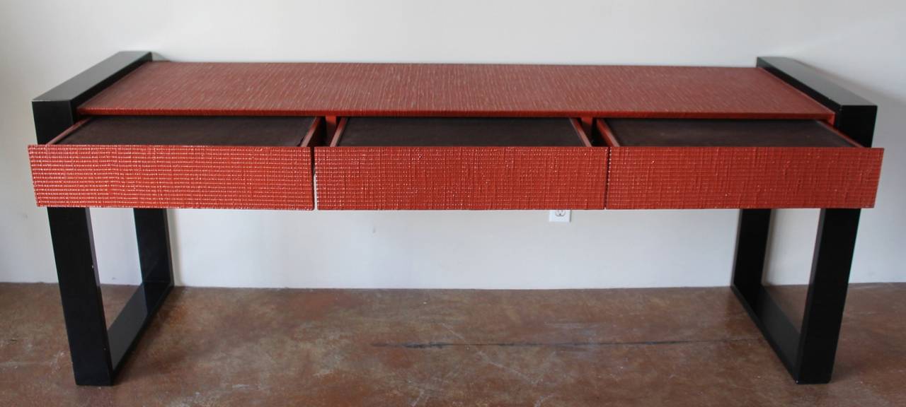 Console with a waffle texture, blood orange, lacquered finish and black lacquered boxed frame legs. Rectangular shape with a minimalist design. 3 drawers that function smoothly, lined in original felt for flatware. A great piece and well made.