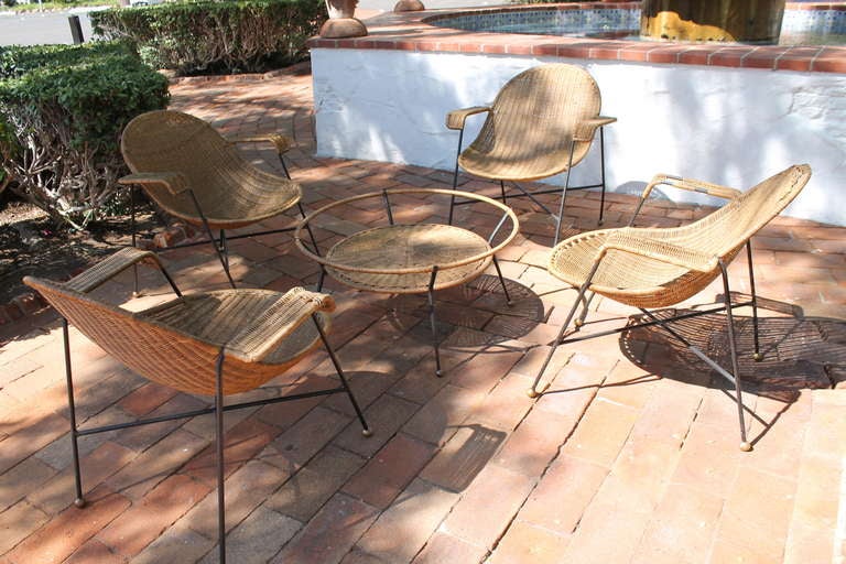 Amazing wicker and iron chair and table set from Mexico City, circa 1950s. The four chairs have a wide, spoon shape seat with a strong, heavy iron base on bronze spheres. The table is wicker with an iron base on bronze spheres, and with the option
