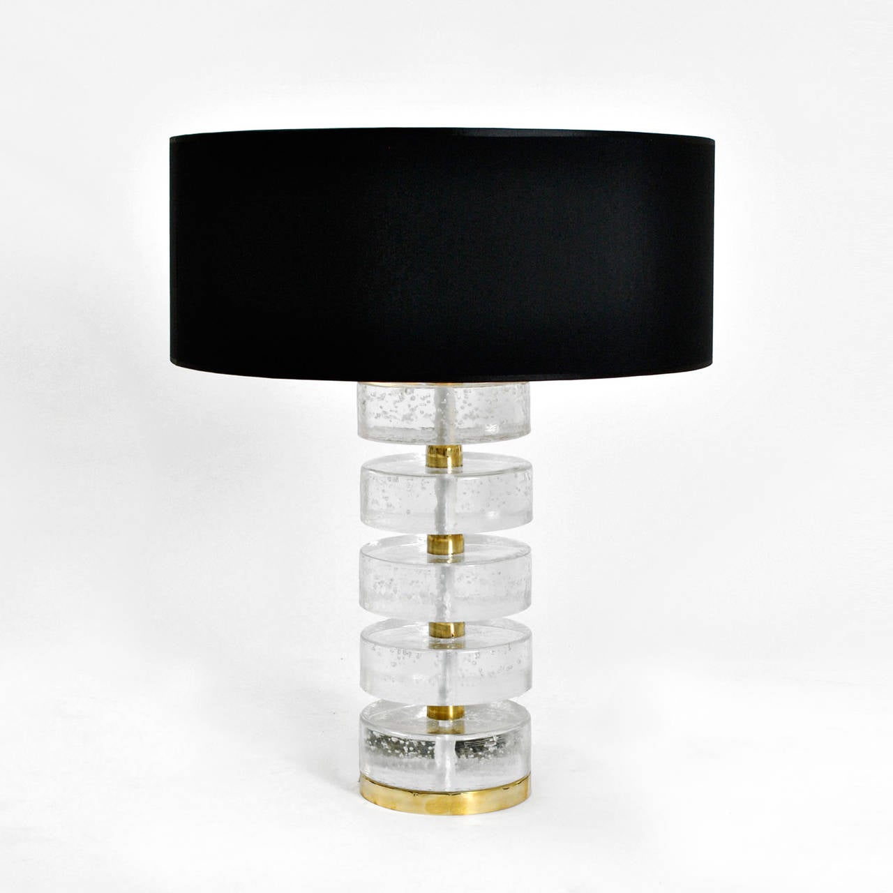 Pair of table lamps made in solid rock crystal shaped on a disk form composed by pieces of crystal and brass. Lamp shade made in black and golden 