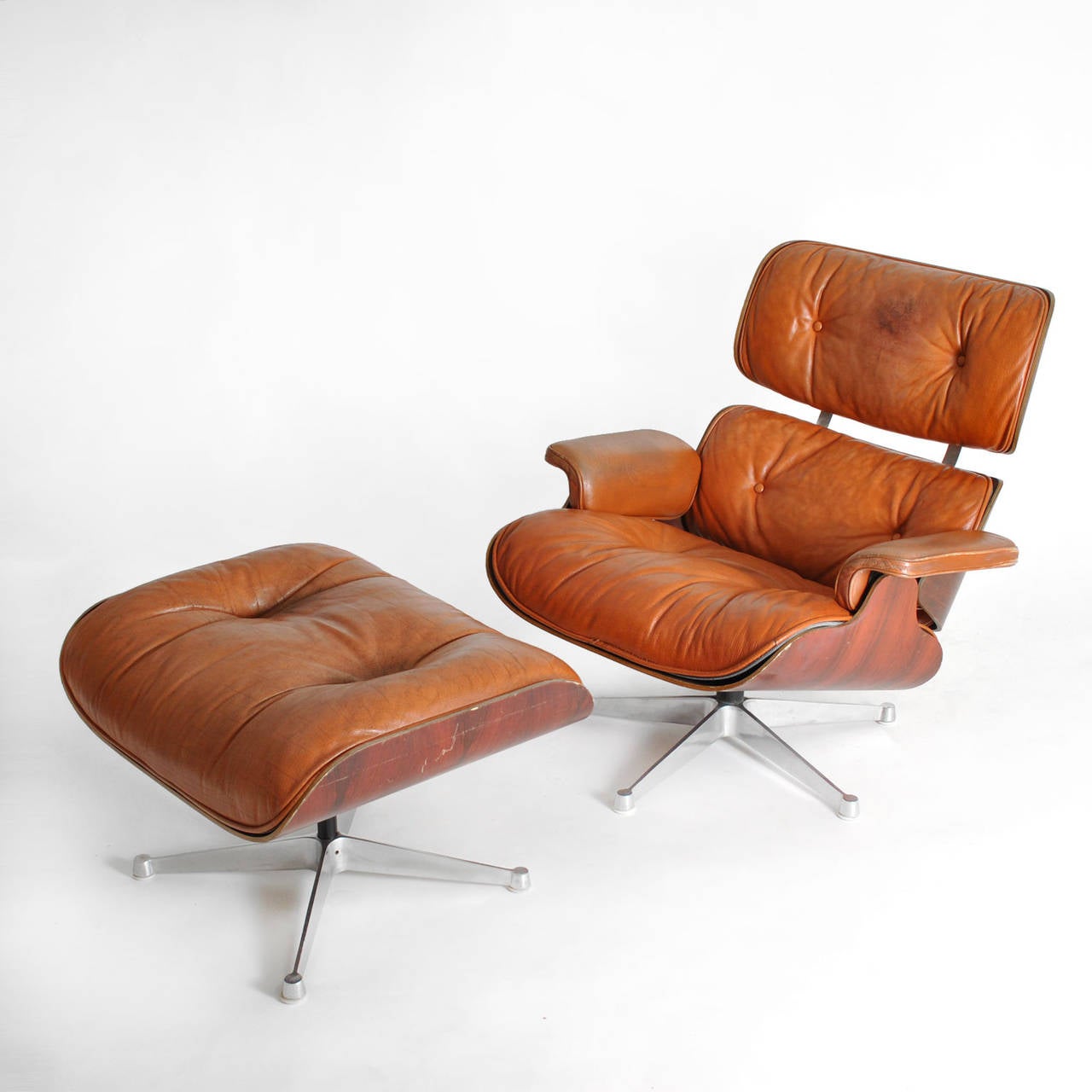 Lounge Chair and Ottoman designed by Charles and Ray Eames and Herman Miller edited by the late fifties , made of plywood , finished in rosewood , original cognac-colored leather upholstery . Steel legs with feet finished in pill. 
USA 1950