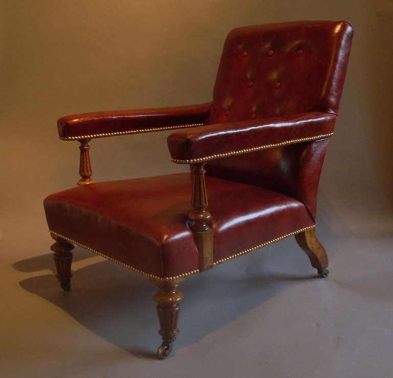 A good 19th century Gillows golden oak and leather library chair; the padded and buttoned upholstered back and padded straight arms, with turned and fluted supports, the deep padded seat with turned and fluted forelegs, with brass castors with a