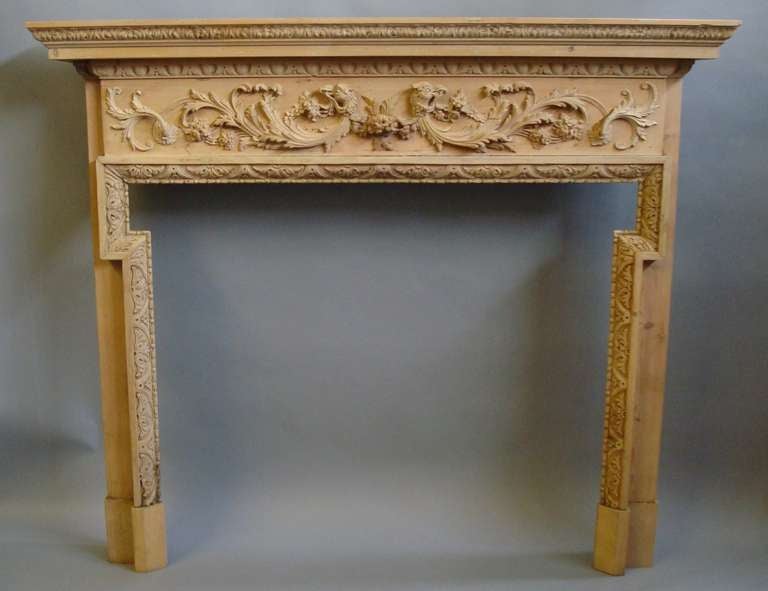 An impressive Georgian carved pine fire surround, the protruding top with a carved moulded edge, above an 'egg and dart' moulded frieze, incorporating deeply carved opposing eagle heads holding foliage in their beaks with flowing acanthus scrolls;