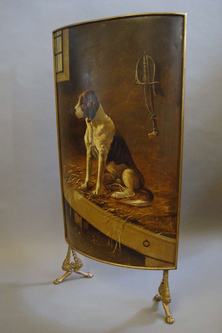 An unusual C19th painted tole firescreen; the bow fronted panel with a gilded moulded edge incorporating a well painted hound seated in a stable, in the background a window and his dog collar and riding crop hanging up; raised on gilded acanthus