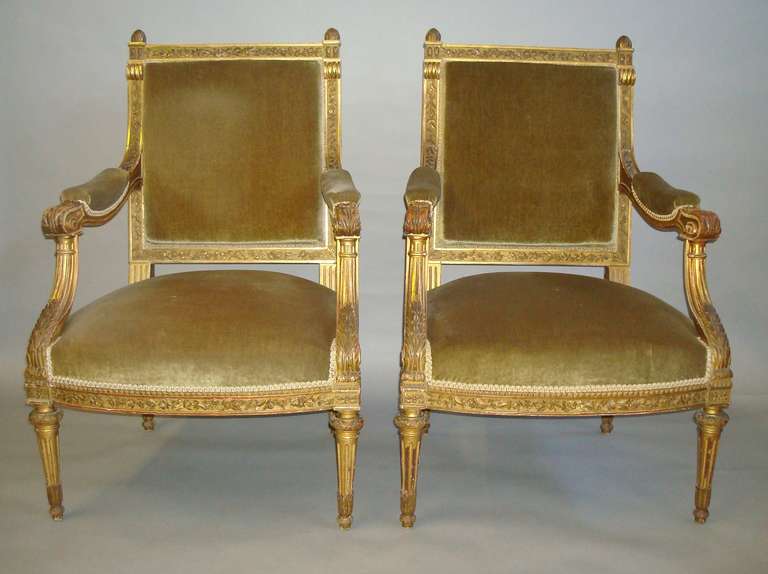 An impressive C19th pair of carved giltwood fauteuils/ open armchairs; the square padded back with a carved foliate frame, the top rail with raised finials, the scroll padded arms and swept arm supports both with scroll and acanthus carving; leading