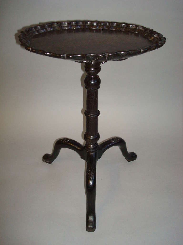 A rare C18th Irish bog oak kettle stand of very small proportions; the oval top with a double tier pie crust edge, raised on a ring turned tapering column with exaggerated shaped shell carved legs, terminating in pad feet.  The underside of the top,