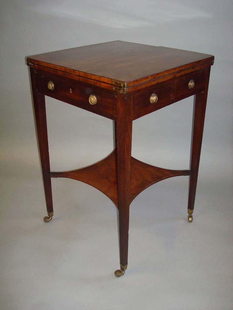 A good George III mahogany patience table, the square fold over top supported on side lopes disguised as dummy drawers; the frieze with a single mahogany lined drawer and dummy drawers to sides and reverse, all with ebony stringing and with original