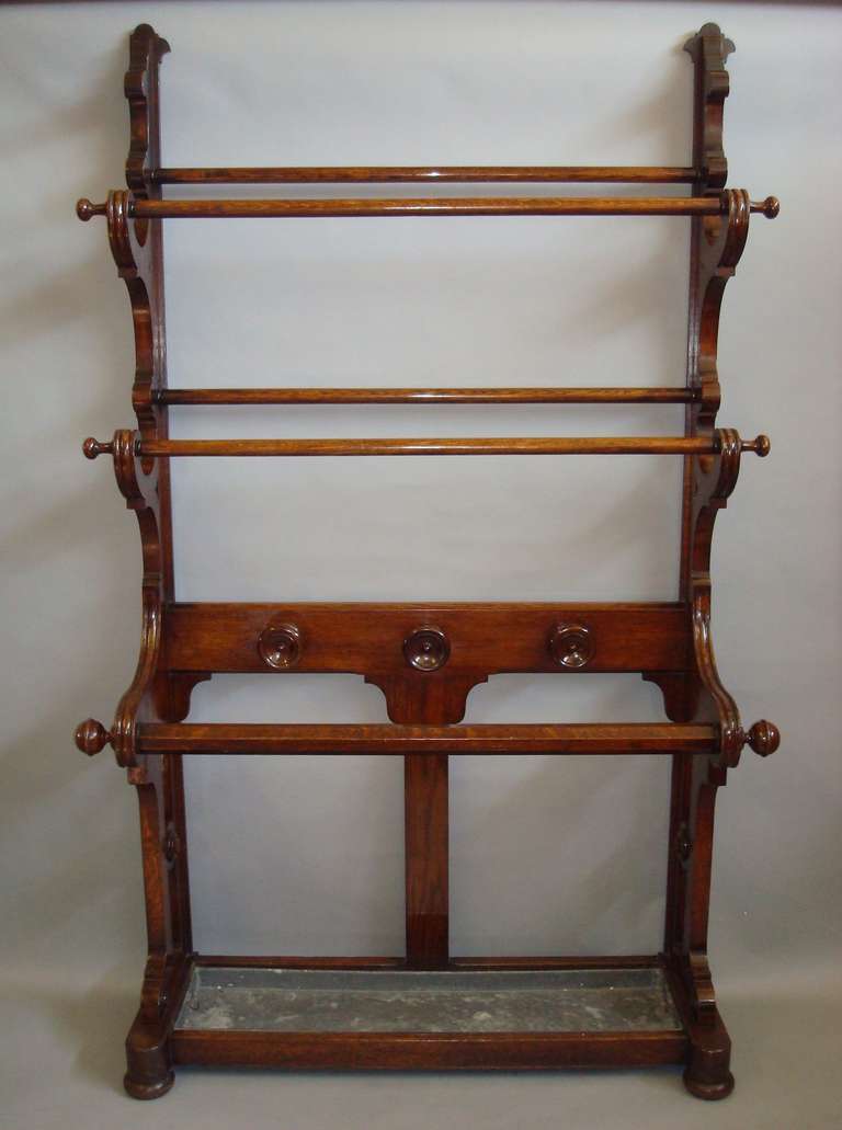 A good mid C19th oak hall stand, the shaped uprights supporting four turned rails with turned finials; the sides with an open arch and central boss with roundel, below there are three large protruding roundels for stick supports; the front rail