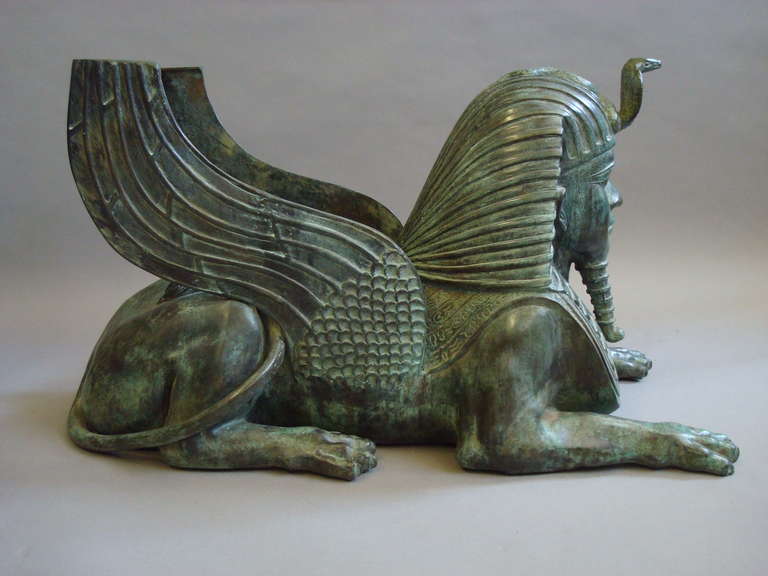 A rare bronze sphinx table base/ sculpture of large proportions; of typical sphinx form incorporating a cobra protruding from the head dress and hieroglyphs along her back, the wings and cobra with a flat top for the support of glass or marble table