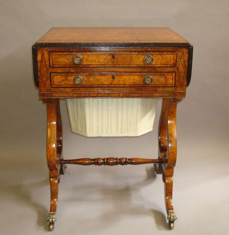 A good Regency burr elm and ebony inlaid work table; the rectangular 

top with drop flaps incorporating rounded corners, wide ebony stringing 

and ebonised reeded edge, above two oak lined frieze drawers with 

brass ring handles above a