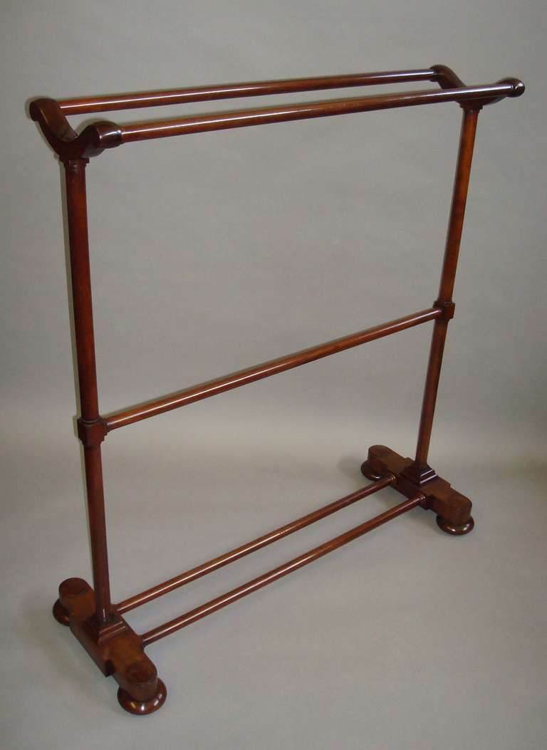 A good large Regency mahogany clothes/towel rail, the twin turned top rails supported on scroll brackets, raised on turned uprights with a central rail, the platform supports of break fronted form with large domed roundels; incorporating twin turned