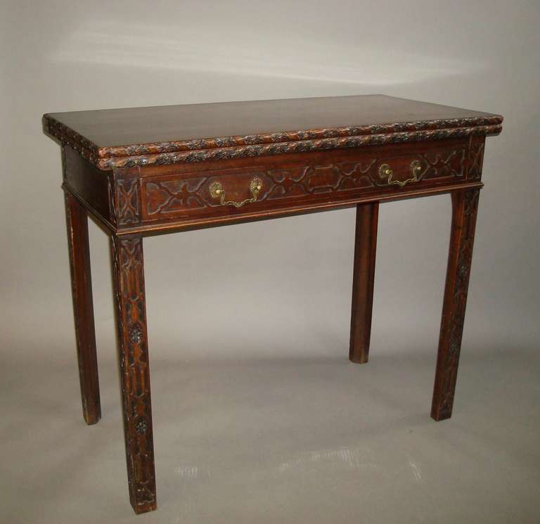 A near pair of C19th Chippendale style mahogany tea tables, the rectangular fold over top with carved flower head edges, above an oak lined frieze drawer with Chinese Chippendale style blind fret carving and brass rococco swan neck handles; raised