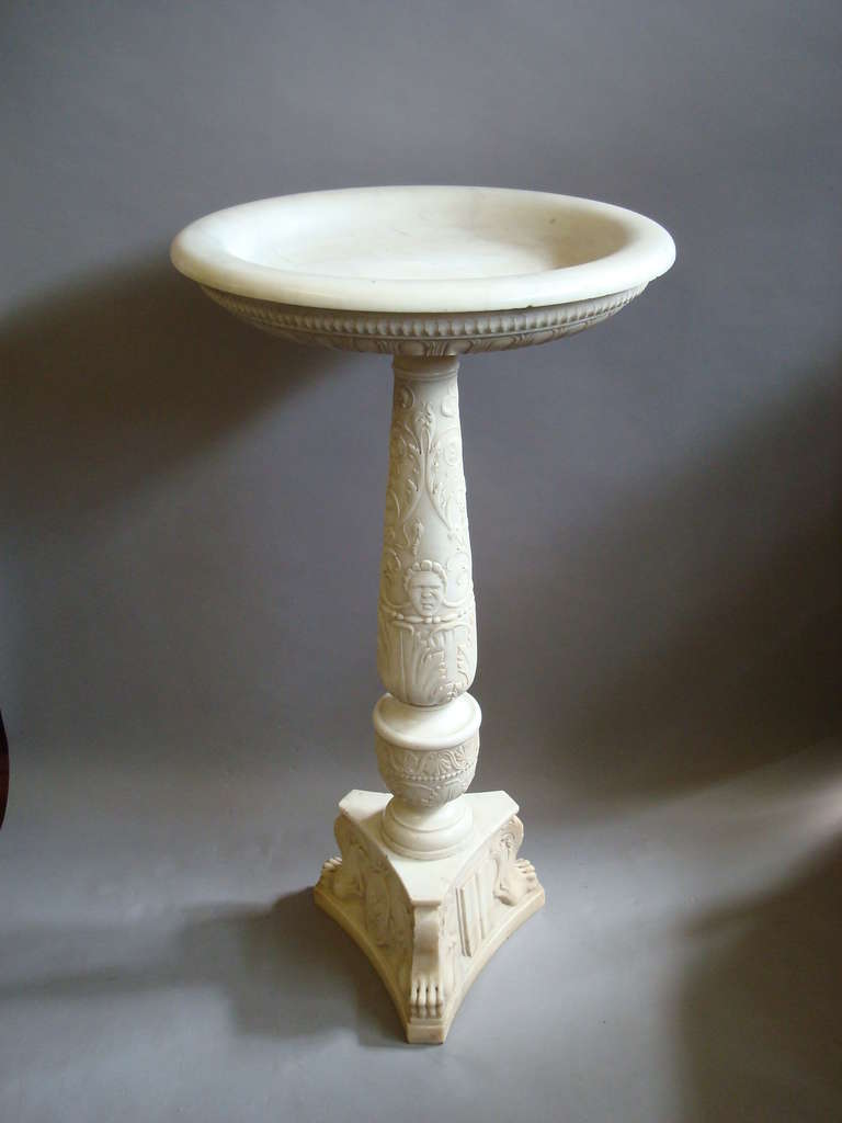 An impressive early C19th carved marble tazza on pedestal; the circular shallow bowl, with a bold moulded rim and gadroon carving to the whole of the underside, the tapering column intricately carved with trailing foliage incorporating a pair of