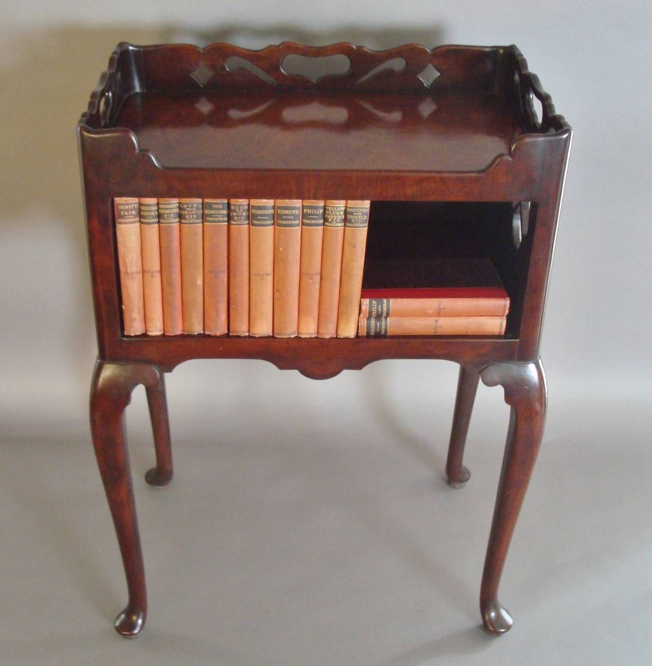 An exceptional Georgian mahogany book table, of small proportions, the very well figured rectangular tray top incorporating a shapely gallery with pierced decoration including shaped carrying handles; above the open compartment with pierced