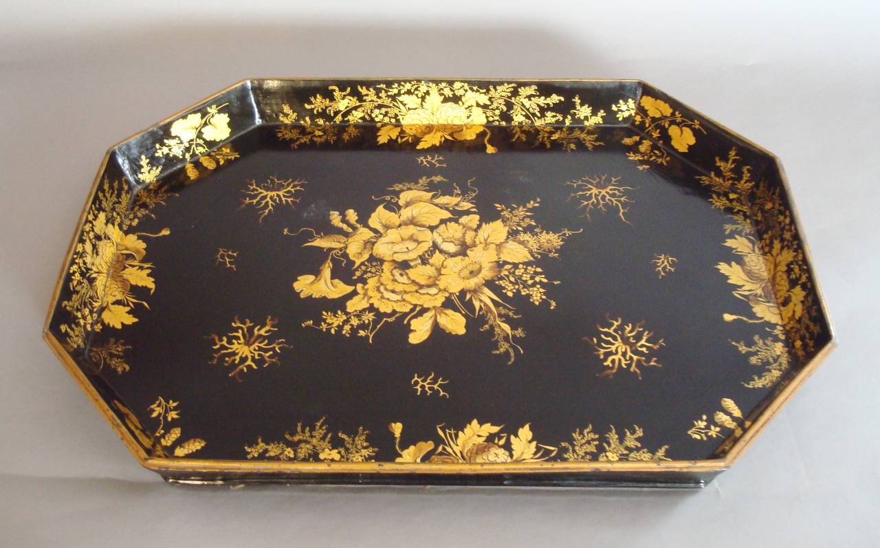 A good Regency papier mâché tray, retaining all the original decoration, having a flared gallery with a thin moulded edge, all profusely decorated with flowers and foliage in two tone gilt on a black background; the underside of the tray lined
