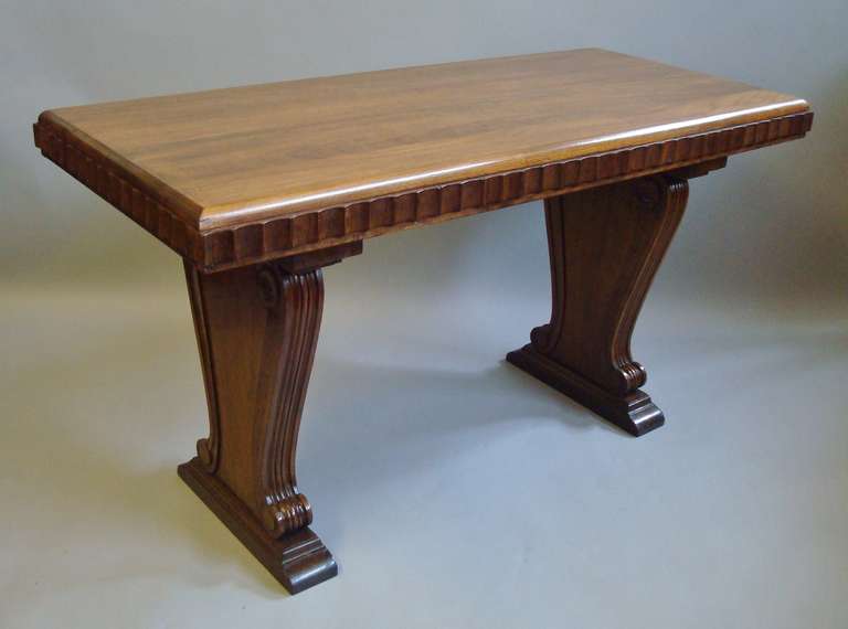 A stylish early 20th century walnut centre table in the Art Deco style; the rectangular top with a thumbnail moulded edge above a serrated moulded frieze, standing on scrolled end supports with sledge feet.