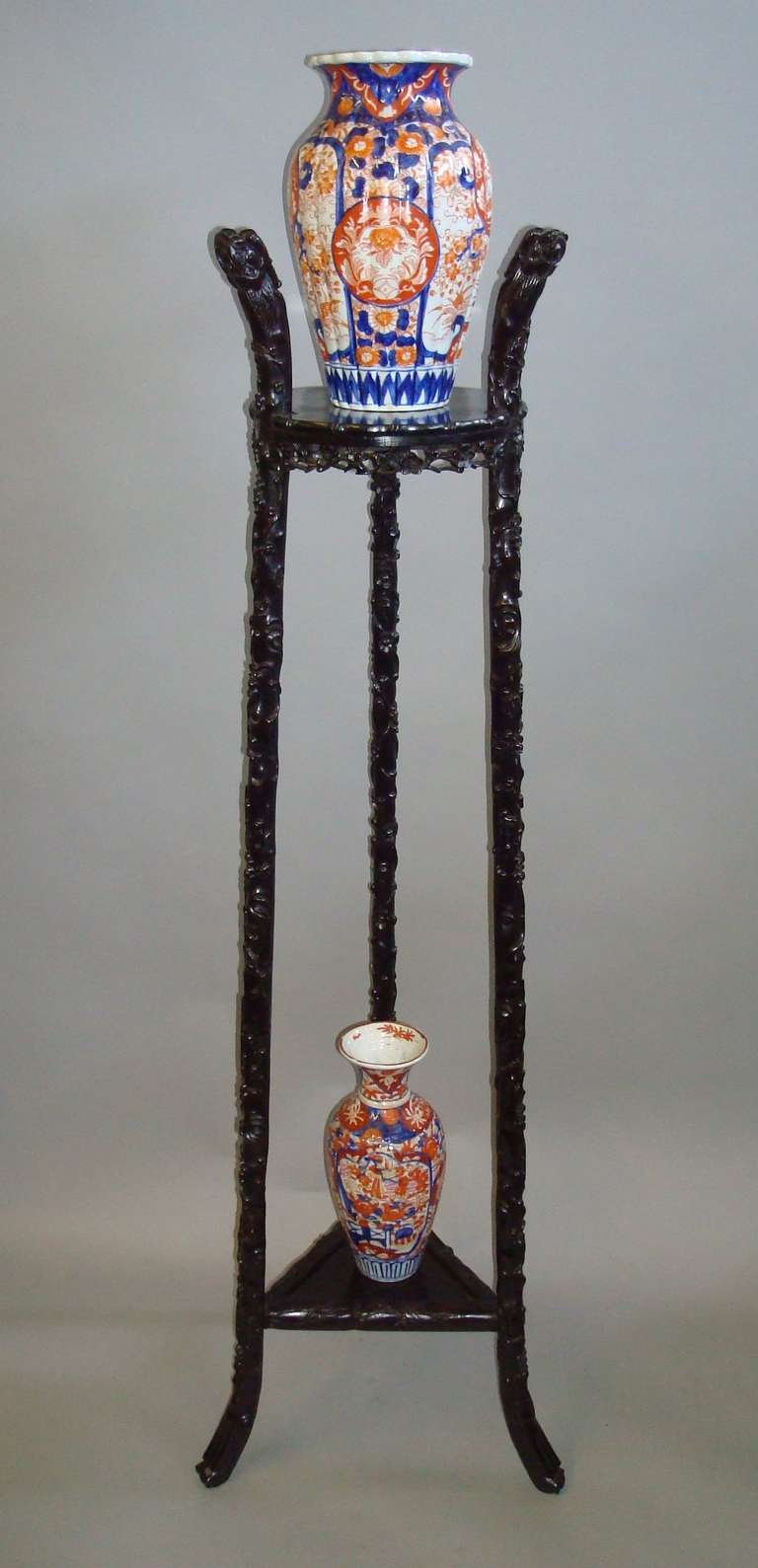 A C19th Chinese carved and ebonised 'Hongmu' stand; of tapering form, the circular top tier with a faux bamboo moulded edge and a carved pierced foliate apron below; raised on three supports carved with trailing foliage and blossoms, terminating in