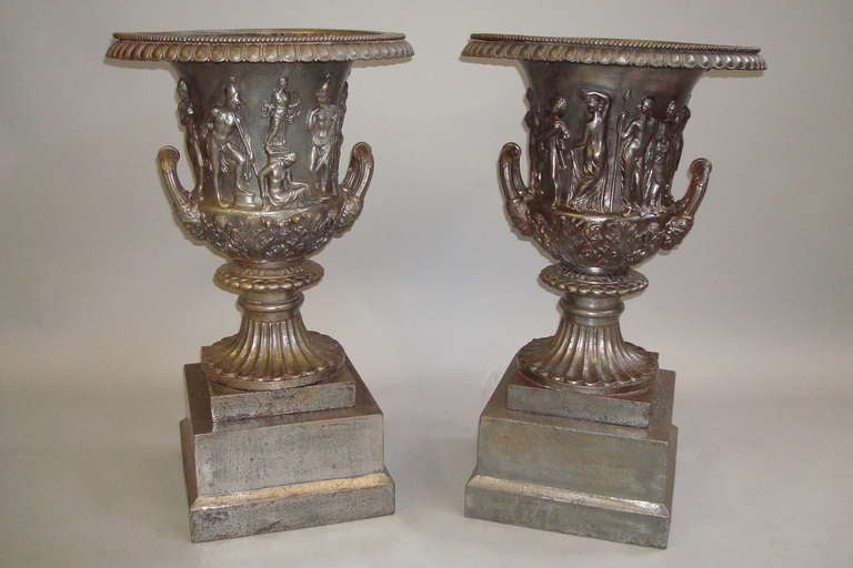 Good quality mid-19th century pair of burnished cast iron campana urns. After the Medici & Borghese vases. Each with an everted rim above a body with numerous classical figures and acanthus leaves below, the loop side handles with masks, raised on a