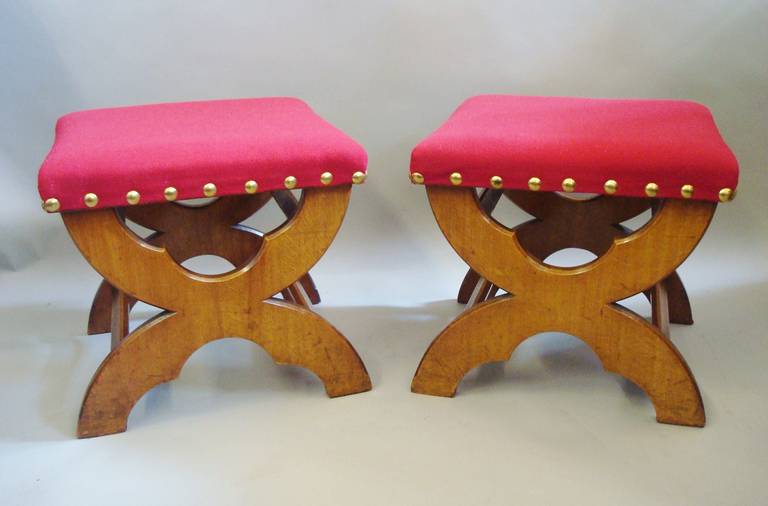 A 19th century pair of Gothic golden oak stools, the square tops upholstered in red baize cloth, with large brass studs; the  