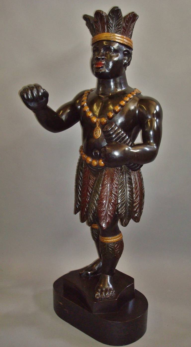 A rare 19th century American tobacconist advertising figure of large proportions, well carved and polychrome decorated, modeled as an African American, the head dress with a gilt band and tobacco leaves, wearing a large gilt beaded necklace and