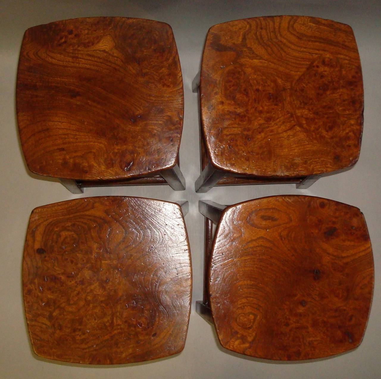 Late Georgian set of four burr elm and oak stools; the burr elm square tops with curved sides raised on oak bases with plain aprons, the four square tapering legs joined by traditional stretchers; of pegged construction.  Excellent colour and patina.