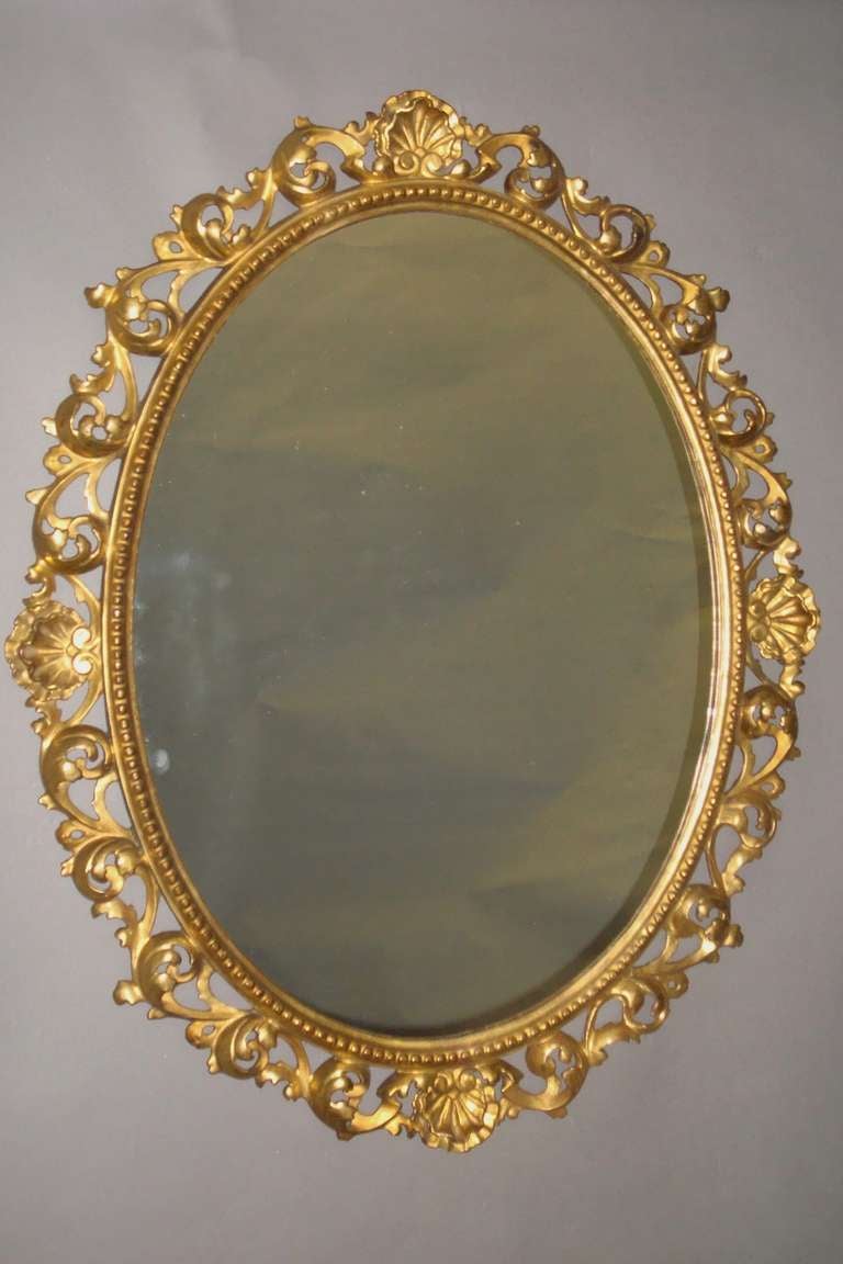 A mid-19th century pair of Florentine carved giltwood wall mirrors. The oval frames with four scalloped shells joined with pierced scrolling; the inner frame with a beaded decoration. With lovely original water gilding, showing small signs of