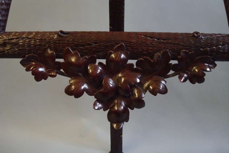 A late 19th century unusual Black Forest carved easel, the whole carved to simulate branches with bark and knots.  The uprights with carved pegs to adjust the height of the painting.  The cross rail with a carved apron of foliage.  The back support