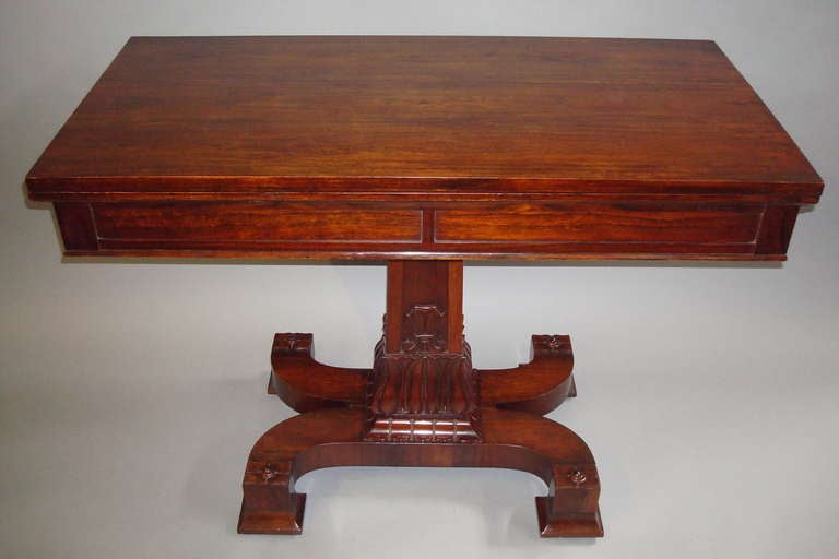 A good Regency rosewood fold over tea table of large proportions.  The rectangular fold over top revealing a well figured interior on a panelled freize incorporating a drawer on each end; on a tapering carved lotus flower column; raised on a