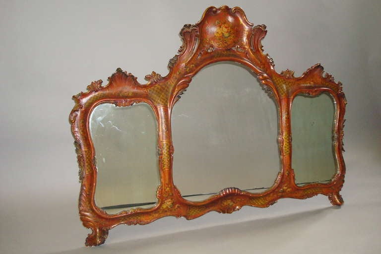 C19th Venetian decorated wall mirror; the cartouche top with decorated with flowers; the carved frame incorporating three mirror plates.  Decorated with trellace panels and sprays of flowers on a red background with gilt highlights.
Good