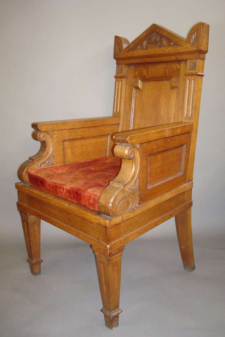 Mid C19th imposing oak throne armchair, the top of architectural form with carved foliate decoration above a recessed panelled back, with carved flower heads to each corner, flanked by fluted uprights with carved paterae, the arms with panelled