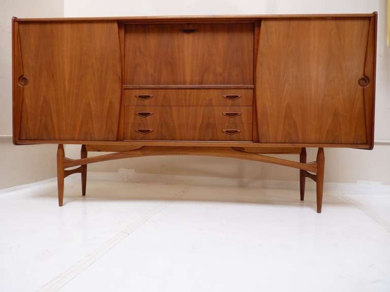 Stunning Danish Credenza or Bar Cabinet in Walnut. This is perhaps one of the best looking Danish Case Pieces we have seen to date, with incredibly detailed  and sculpted base, handles, recessed doors, and beveled edges. It is stamped, 