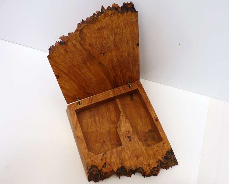 A gorgeous, hinged jewelry box crafted from olive burlwood. The face of the burl is left raw and untouched and gives this unique piece a beautiful, organic feel. The remaining surfaces are smooth and refined, adding a luxurious texture that provides