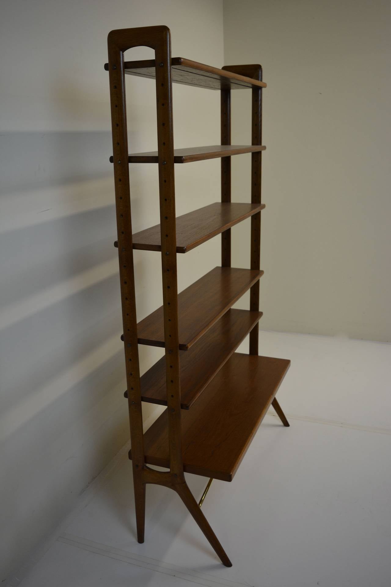 Kurt Ostervig Bookshelf of teak with oak vertical supports and brass braces, circa 1960's. All shelving is adjustable and can be raised, lowered, or removed.  Piece has been restored.