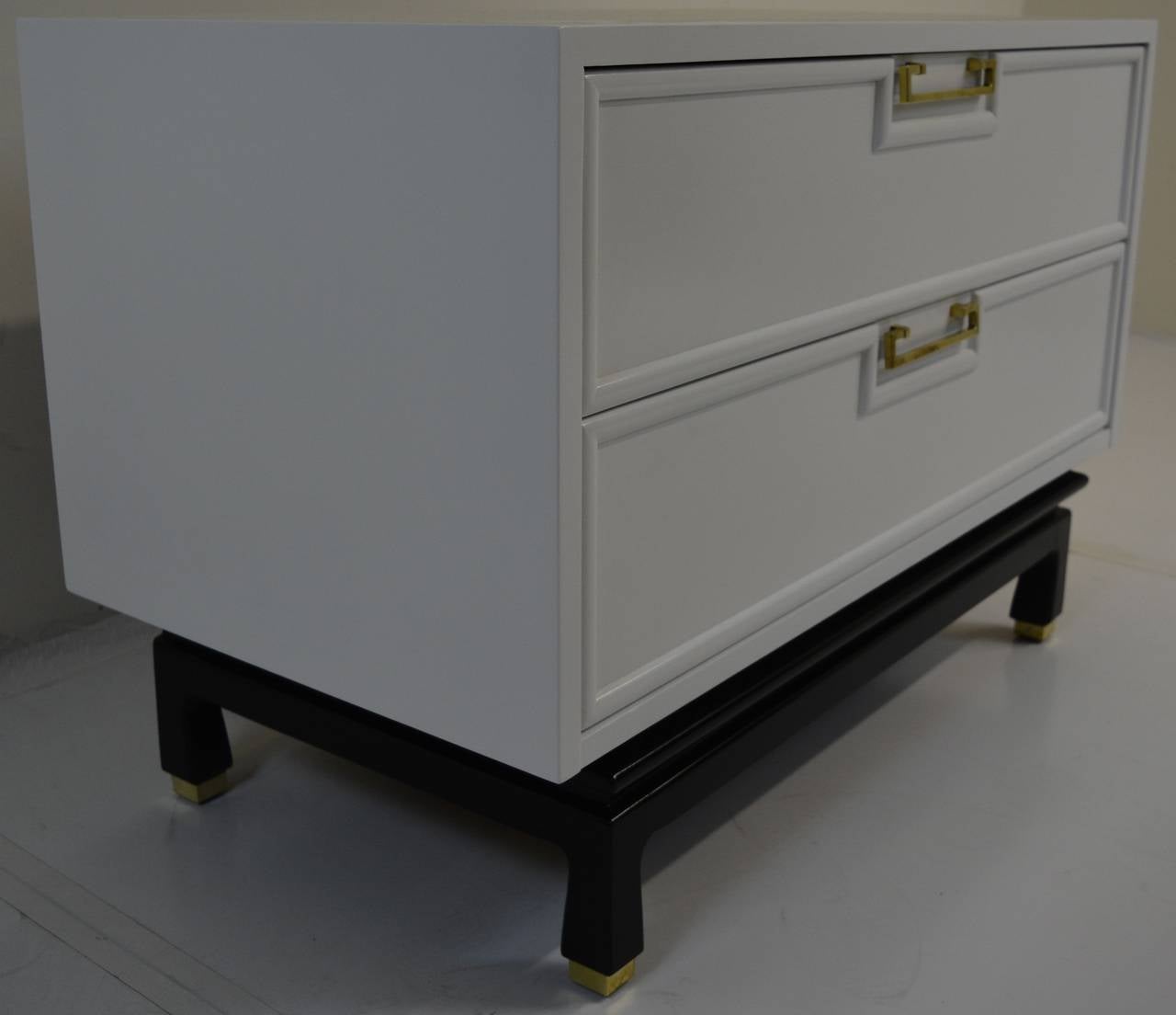 Decorative lacquered chest with brass accents manufactured by American of Martinsville. Solid brass handles and sabots pop against a white lacquer and black lacquered base. Restored condition and ready for installation.