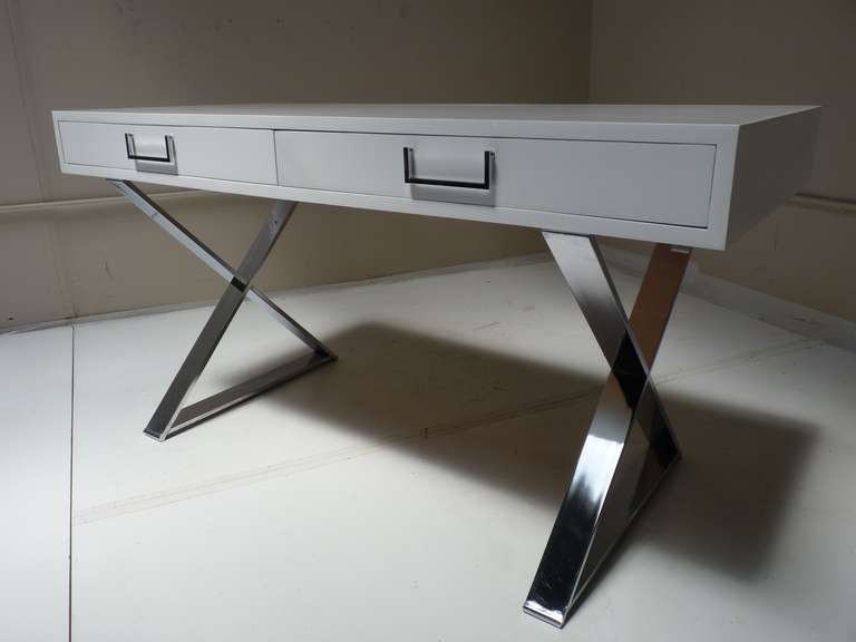 A white lacquered campaign desk with two drawers, raised on X-base of polished chrome-plated steel legs by Milo Baughman, circa 1970's.