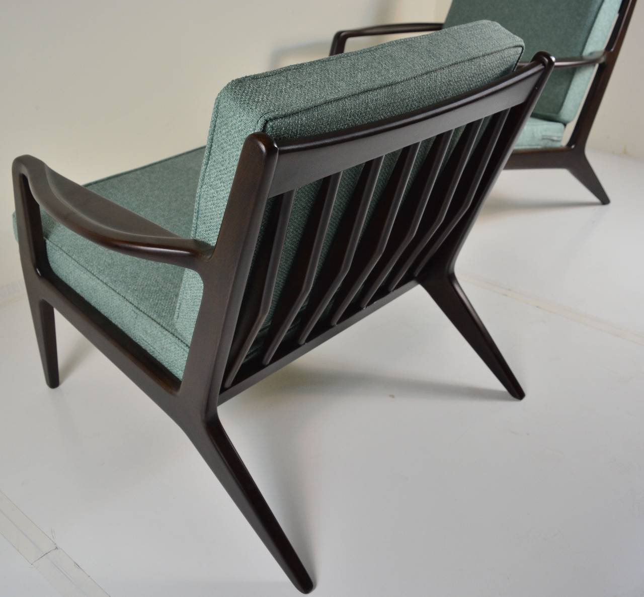Pair of restored lounge chairs by Ib Kofod-Larsen for Selig in dark walnut hue with period style textured fabric.