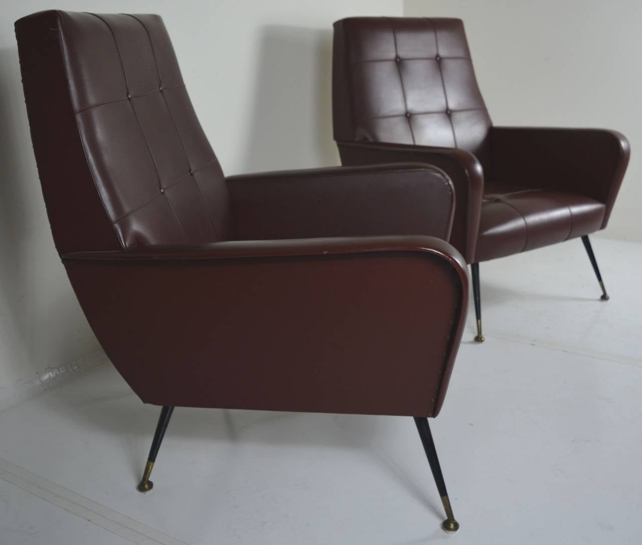 Pair of Masculine, Italian Armchairs in original tufted naugahyde, circa 1960s. Lacquer and brass pronounced legs and straight forward simple lines make these chairs perfect for a MadMen office or lounge! Original upholstery in very good condition