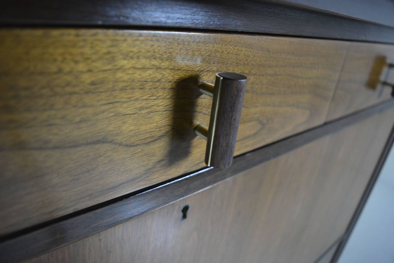 Rarely seen Edward Wormley drop down bar, credenza for Dunbar made of walnut & mahogany, with brass & rosewood hardware. Cabinet is in beautiful original condition with drop down middle section, 3 drawers above, and 1 wide partitioned drawer below--