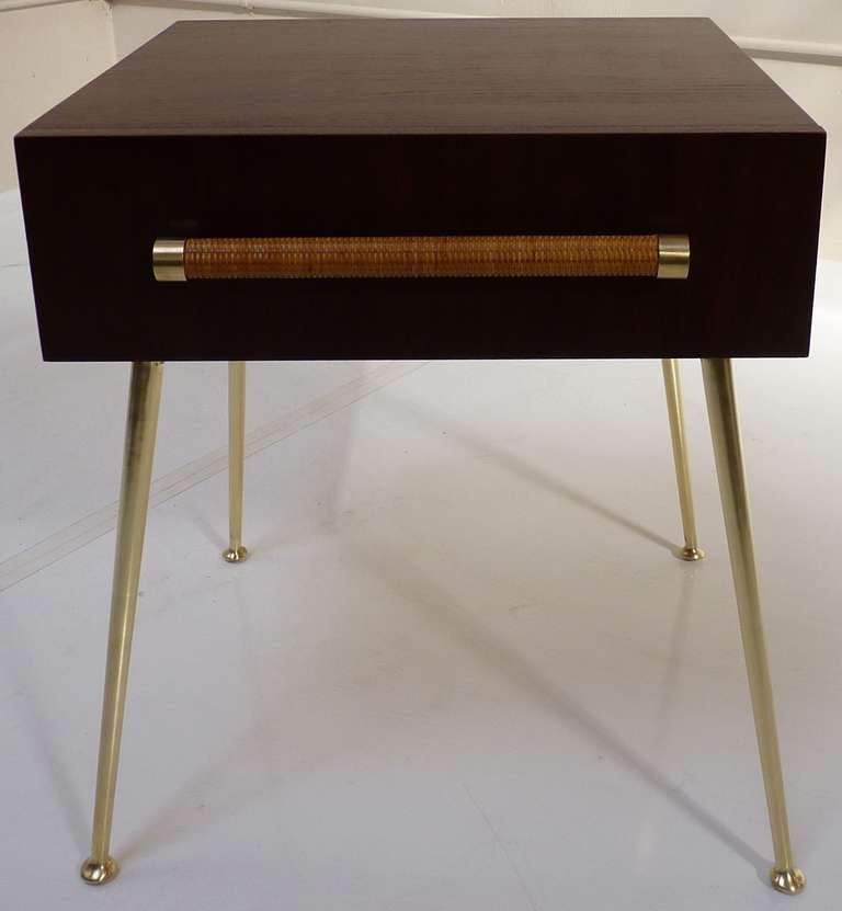 T.H. Robsjohn-Gibbings for Widdicomb nightstand in dark walnut with satin brass legs and hardware. Drawer pull is wrapped with original caning in excellent condition. Wood grain has beautiful figuring as shown. Gibbings for Widdicomb label affixed