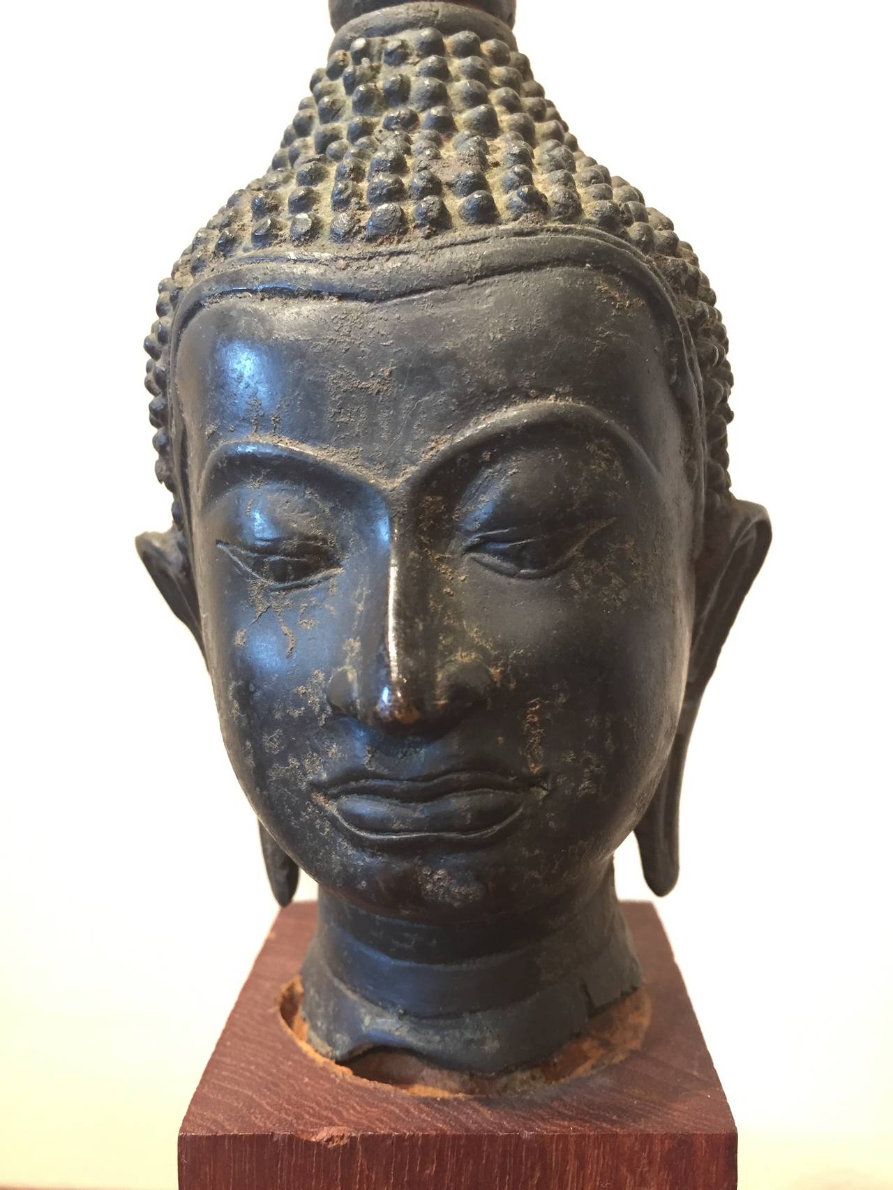 A classically shaped and simply mounted small bronze Buddha head from Thailand, c. 1920. Head lifts off base.
Measurements: 
Buddha: L: 3  D:3   H: 5
On Base: L: 2.25   D: 2.25   H: 8
BH2012