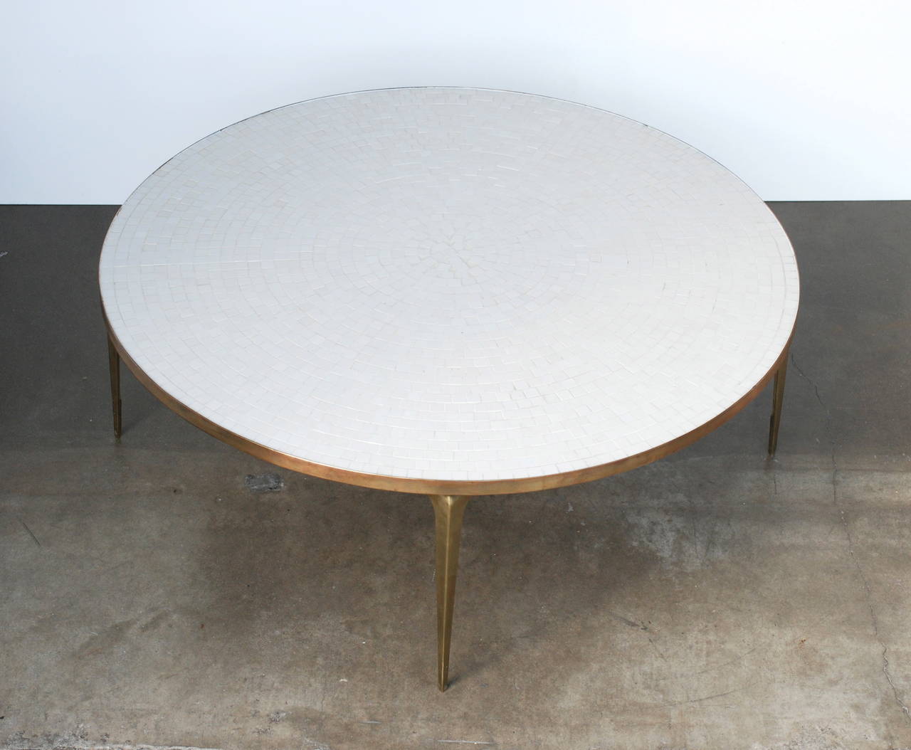 A beautiful table with pointed brass legs that are stamped made in Japan.
The white glass tiles are laid out in a circular pattern which is enhances the form in a clean minimal but Classic way.
We have a coordinating side table in a separate