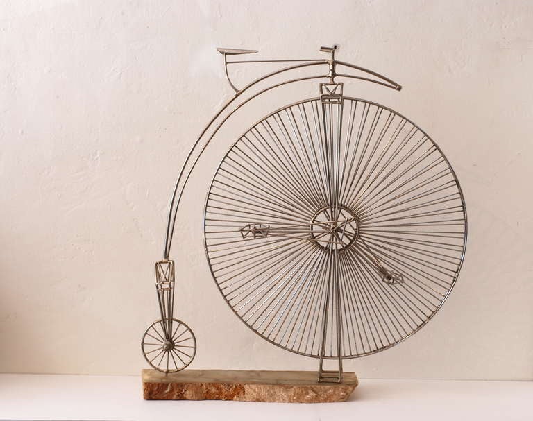 This charming Penny Farthing Bicycle Sculpture is handmade of metal and mounted on a live edge marble base.  The sculpture is removable from its base.  The large front wheel rotates when the pedal is turned.