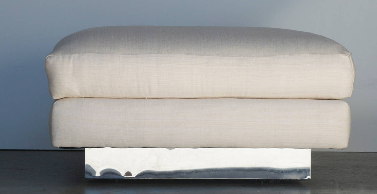 This vintage ottoman attributed to Milo Baughman has been reupholstered in a off white silk. The top cushion is removable. The ottoman has a chrome plated recessed base.