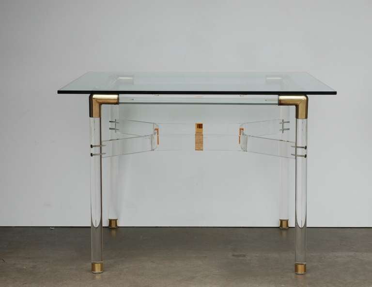 This restored 1970s era acrylic table has brass cross fittings and and brass tipped legs.  The cross bars at the center of the table have a bronze mirror detail.  The lucite has been professionally polished to restore its luster. 
The base is